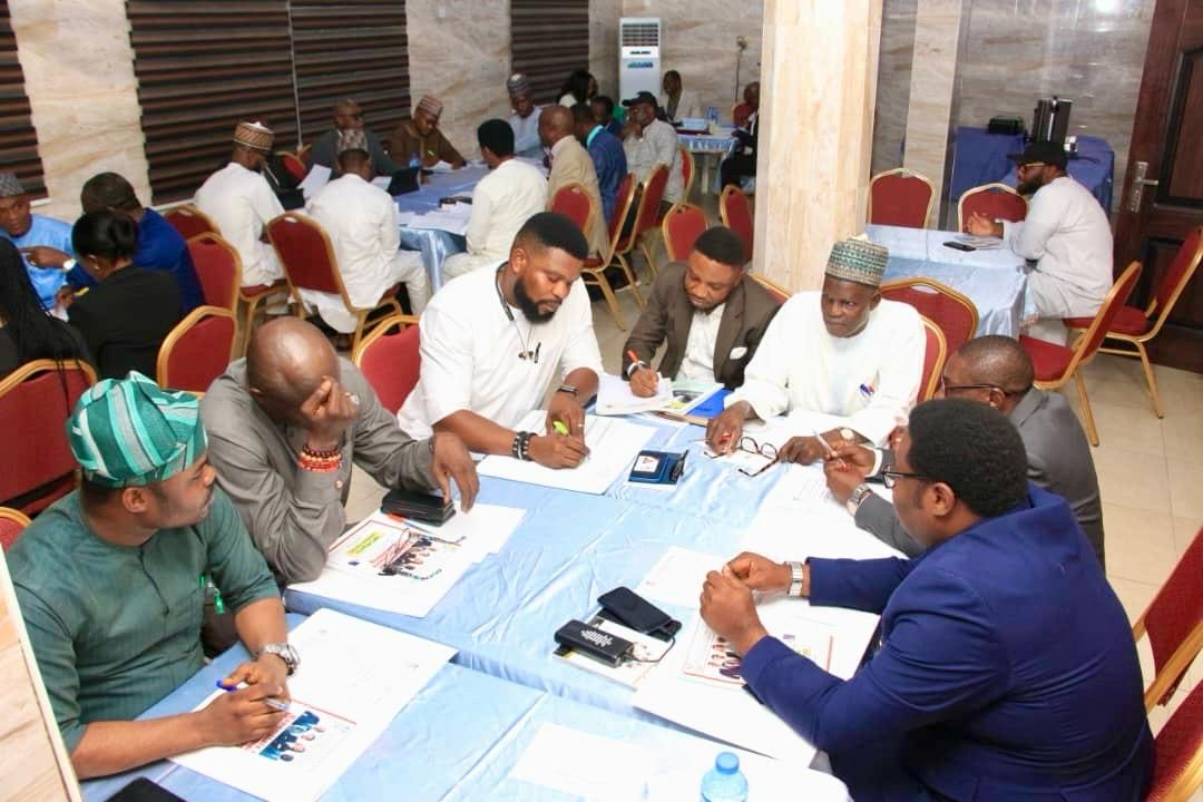 Participants seated around a workshop table completing written exercises while Victor facilitates