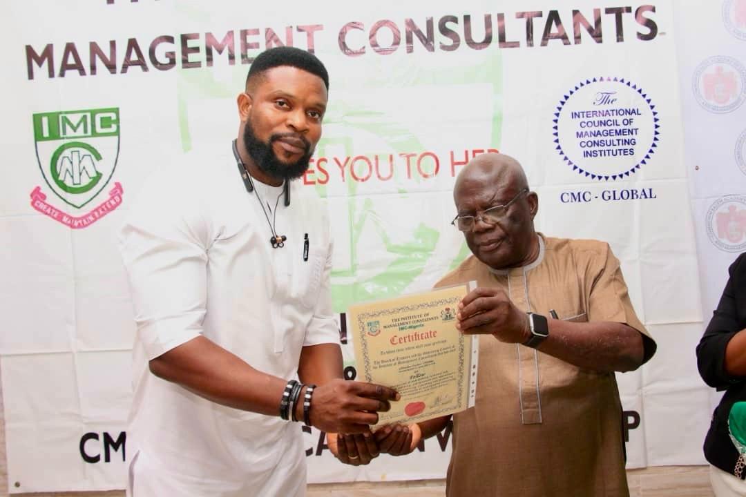 Victor receiving a fellowship certificate from an official of the Institute of Management Consultants