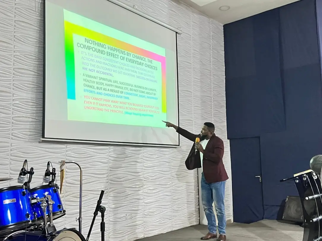 Victor pointing to a projection screen while presenting to an audience