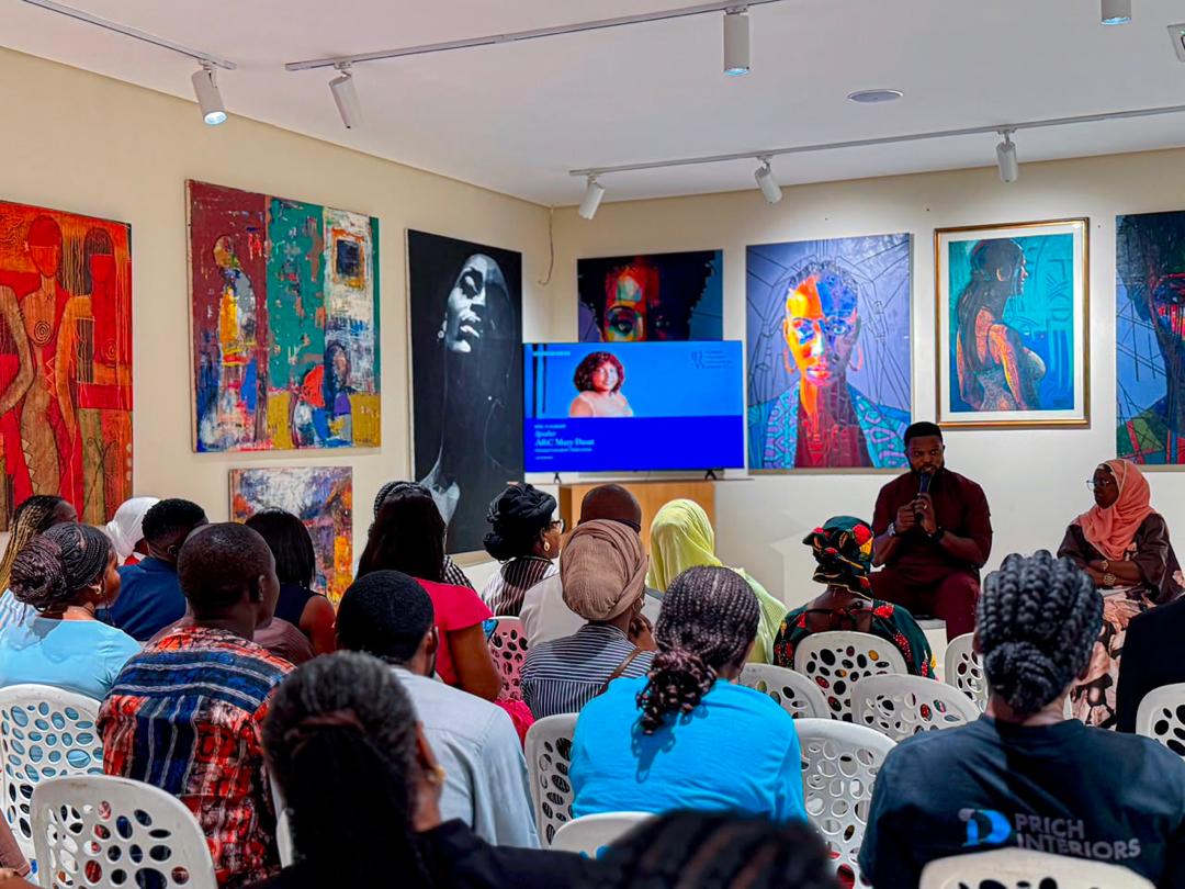 Victor facilitating a conversation with a seated audience in an art gallery setting