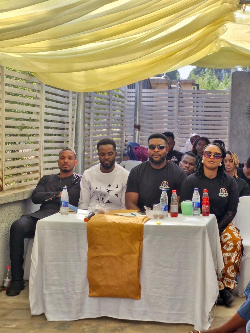 A panel of facilitators seated at a table facing participants at the outdoor session