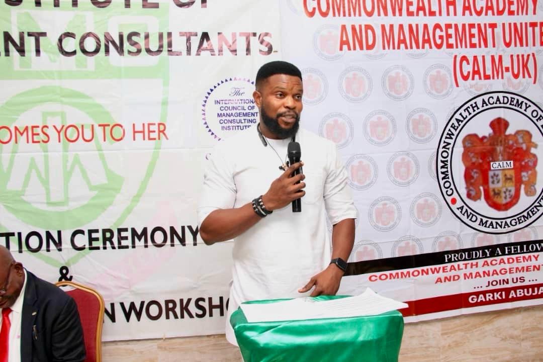 Victor speaking with a microphone at an induction ceremony of the Institute of Management Consultants
